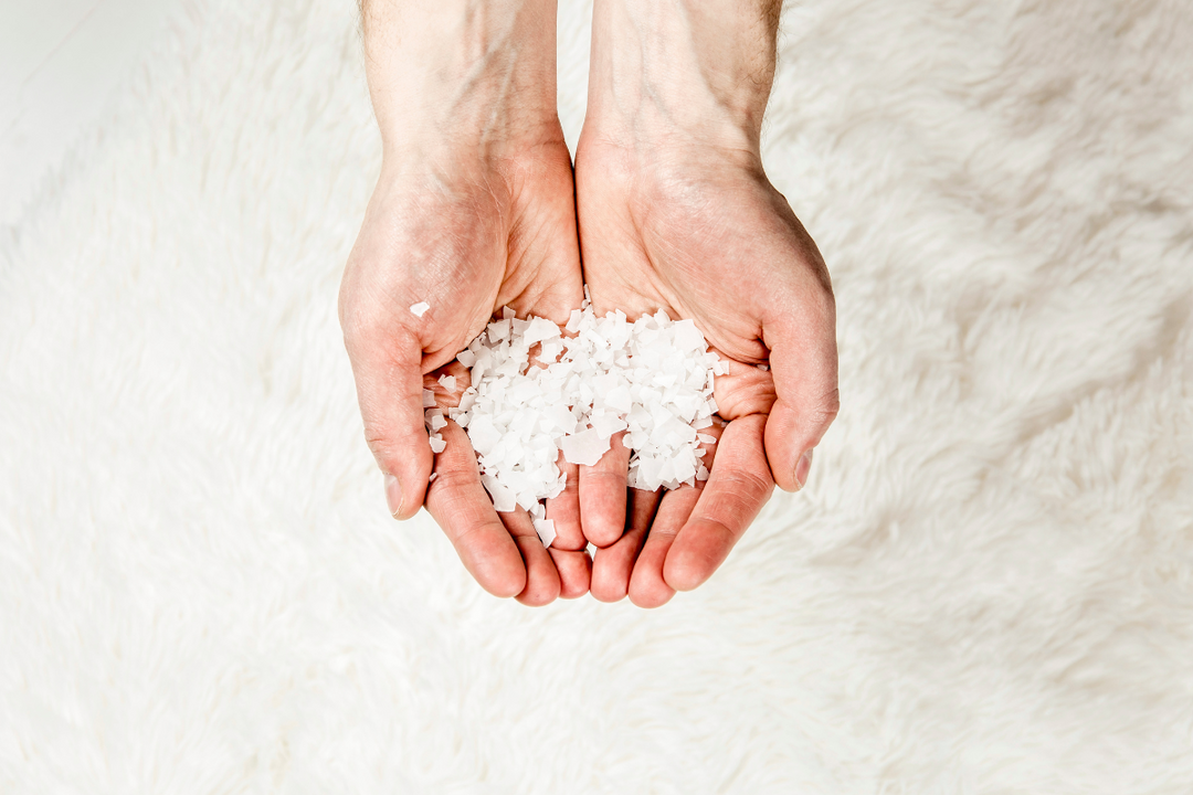 Hands holding magnesium flakes, highlighting the natural form of magnesium for health and wellness.
