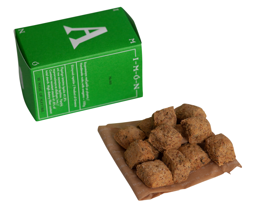 A green rectangular box with a large white letter A on top, shown beside several brown textured cube-shaped food pieces on a sheet of brown paper against a white background.