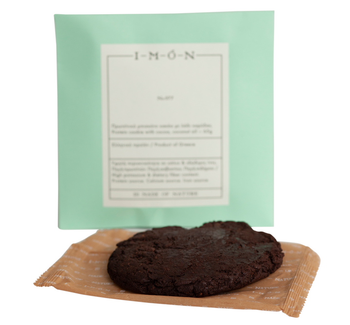 Dark chocolate cookie on a wooden board with a green packaging background
