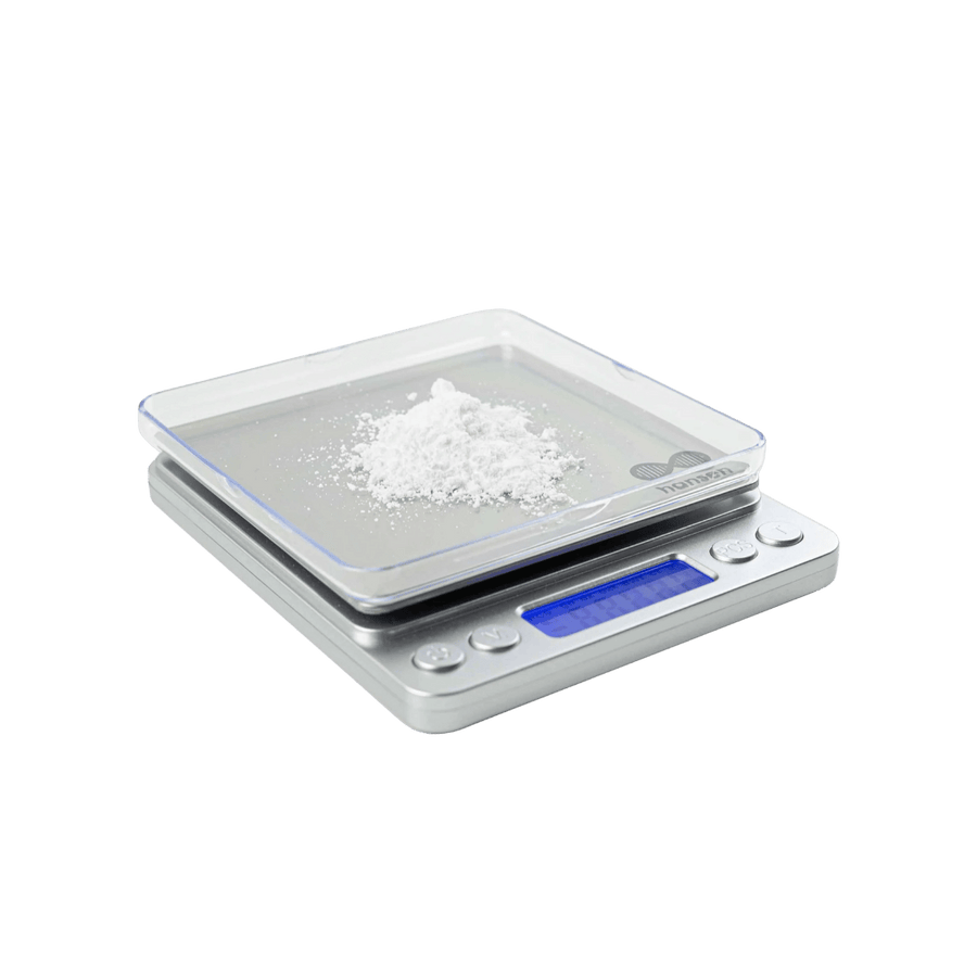 Digital kitchen scale with a small amount of white powder on a clear surface